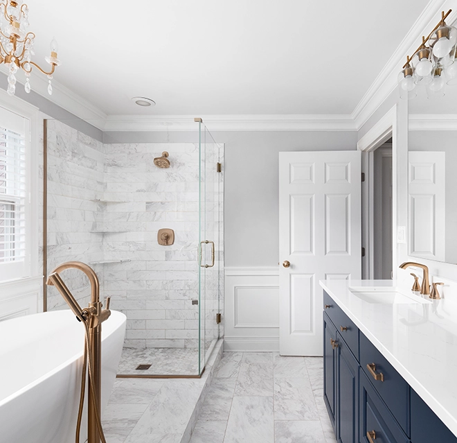 Remodeled bathroom interior featuring a stone and glass shower and freestanding bathtub.