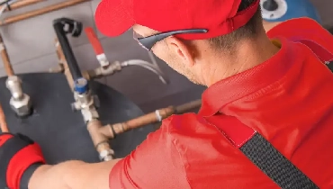 Technician in a red uniform installing a water heater.