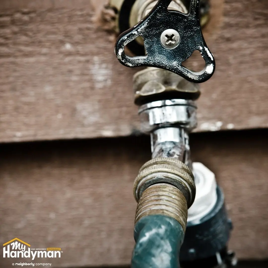 Close-up of a black faucet handle connected to a hose.