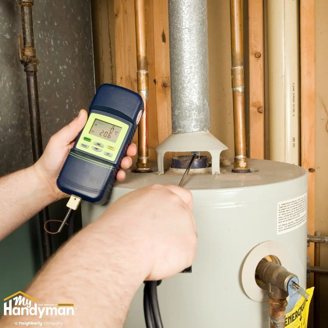 A person tests a water heater using a digital multimeter.