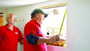 Two Mr. Handyman workers measuring window.